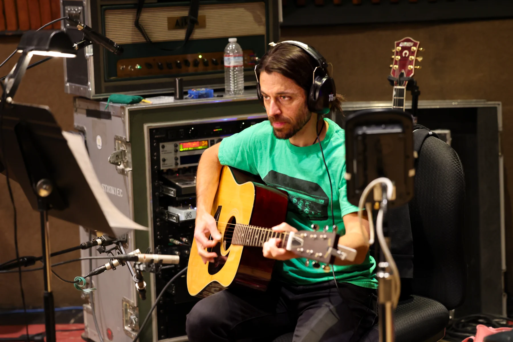 Acoustic guitarist recording beside a studio microphone